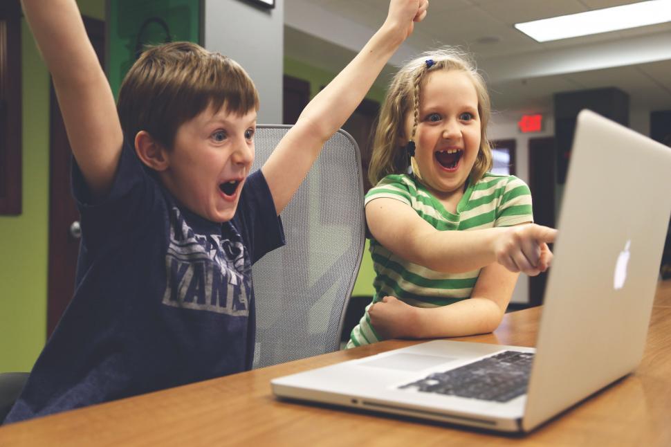 Two children excitedly reacting to a laptop screen