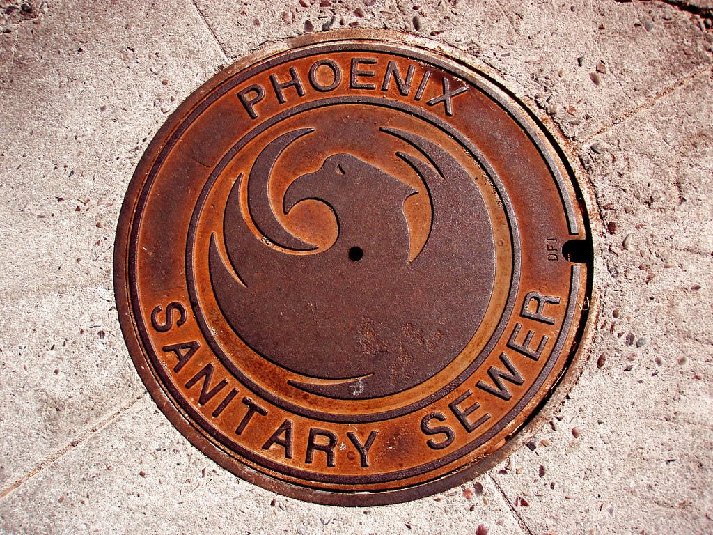 Decorative manhole cover with the City of Phoenix emblem and the text "Phoenix Sanitary Sewer"